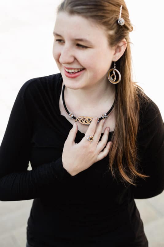 smějící se dívka s prořezávaným náhrdelníkem a náušnicemi z kapslí