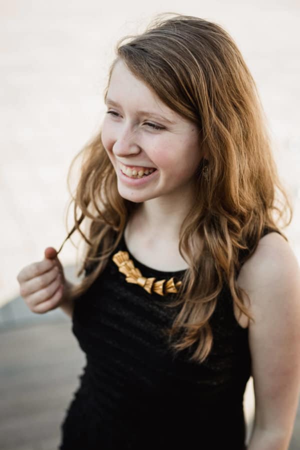 Rozesmátá dívka s elegantním upcyklovaným náhrdelníkem zlaté barvy